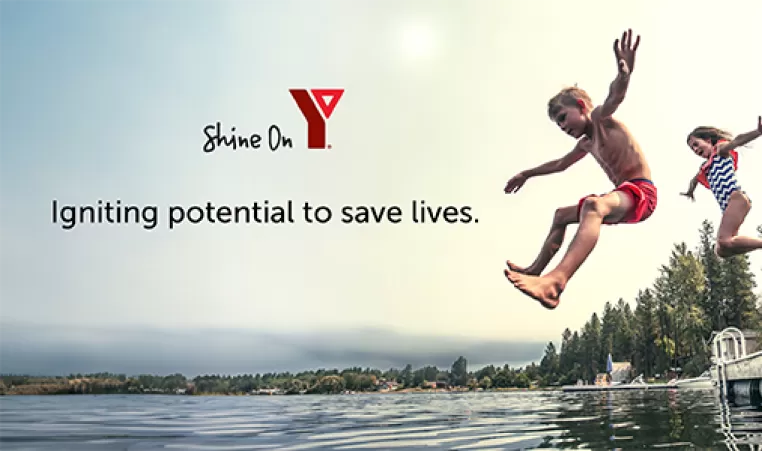 children jumping into lake from dock in summer YMCA Shine On Logo, slogan 'Igniting Potential to Save Lives'