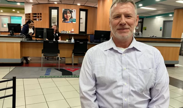 A senior man sits infront of the YMCA membership desk at Ron Edwards Family YMCA