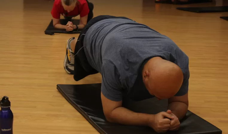 Man does plank during fitness class