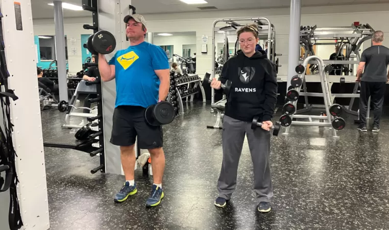 Father and daughter lift weights together in fitness centre