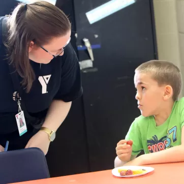 Educator bent over speaking with seated child