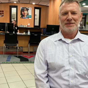 A senior man sits infront of the YMCA membership desk at Ron Edwards Family YMCA